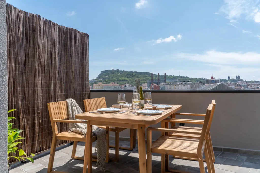 Private balcony with outdoor dining setup overlooking Barcelona’s skyline from the Two Bedroom Apartment at master La Rambla.